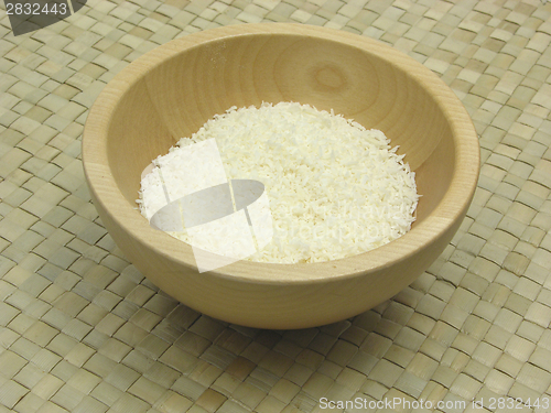 Image of Wooden bowl with coconut flakes on rattan underlay