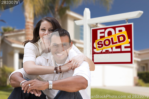 Image of Hispanic Couple, New Home and Sold Real Estate Sign