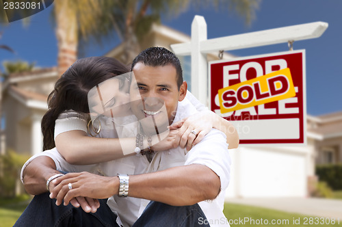 Image of Hispanic Couple, New Home and Sold Real Estate Sign