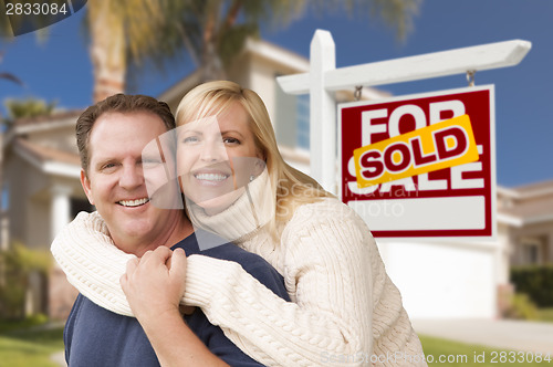 Image of Couple in Front of Sold Real Estate Sign and House