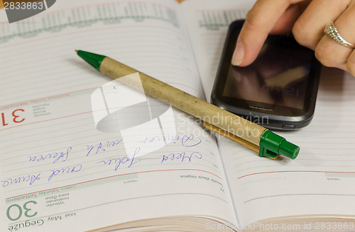 Image of Hand with smart phone and business planner diary 