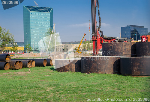 Image of worksite equipment pipes near glass skyscraper 