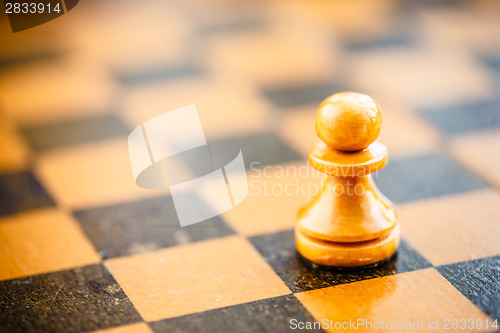 Image of White chess pawn standing on chessboard