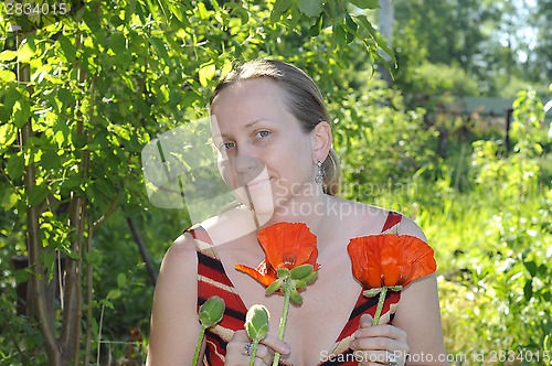 Image of The woman with red poppies in a garden.