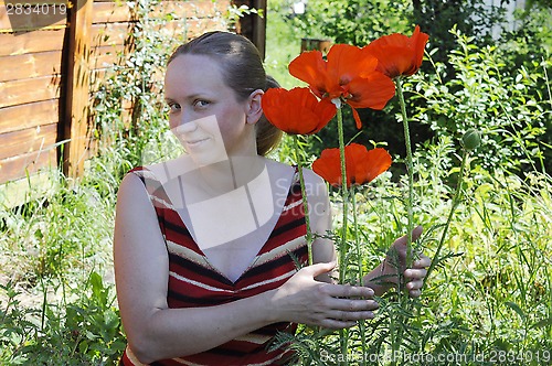 Image of The woman with red poppies in a garden.