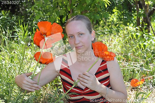 Image of The woman with red poppies in a garden.