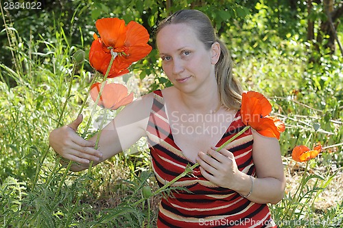 Image of The woman with red poppies in a garden.