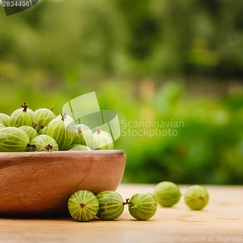 Image of Close-Up Of Gooseberries In Vintage Wooden Bowl On Wooden Table