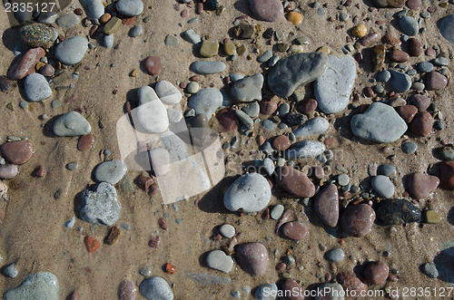 Image of Detail of a wet sandy beach with smooth pebbles