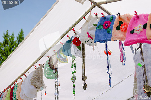 Image of colored baby caps hang on rope village fair 