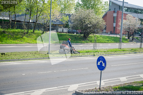 Image of worker with grass cutting machine street pavement 