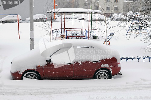 Image of The red car, brought by snow is in the house yard.