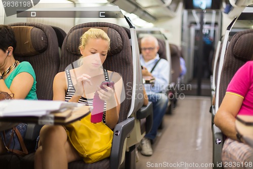 Image of Lady traveling by train using smartphone.