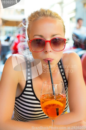 Image of Woman with cocktail in street cafe.