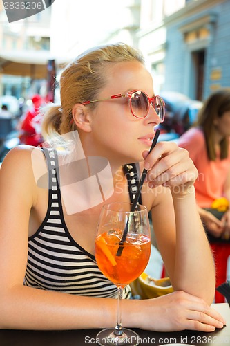 Image of Woman with cocktail in street cafe.