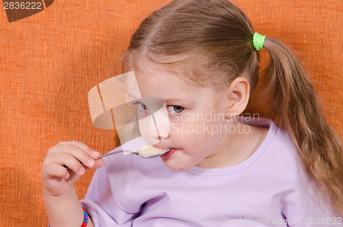 Image of Girl eats honey spoon