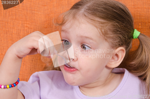 Image of Funny girl squinted with his spoon in mouth