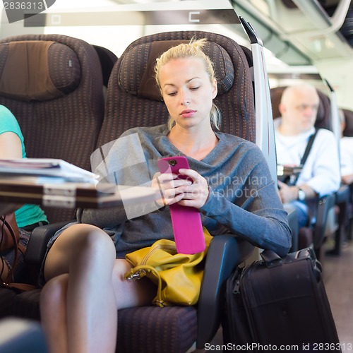 Image of Lady traveling by train using smartphone.