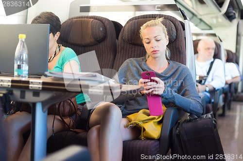 Image of Lady traveling by train using smartphone.