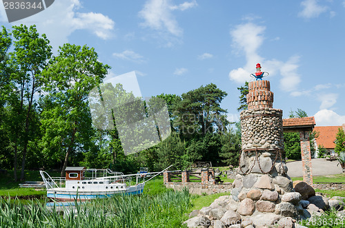 Image of stylized stone lighthouse and small tourist boat  