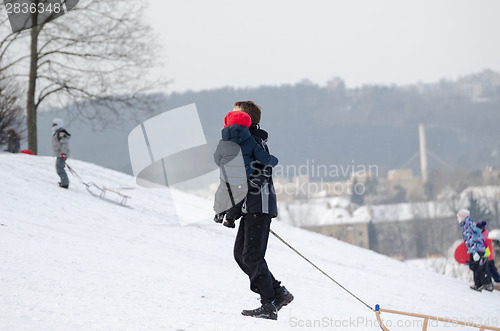 Image of father with son climb up snowy hill in winter time 