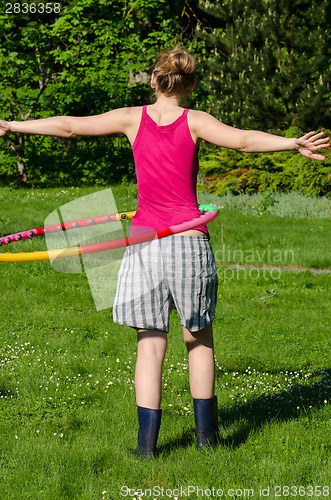 Image of woman turn spin hula hoop ring on waist in garden 