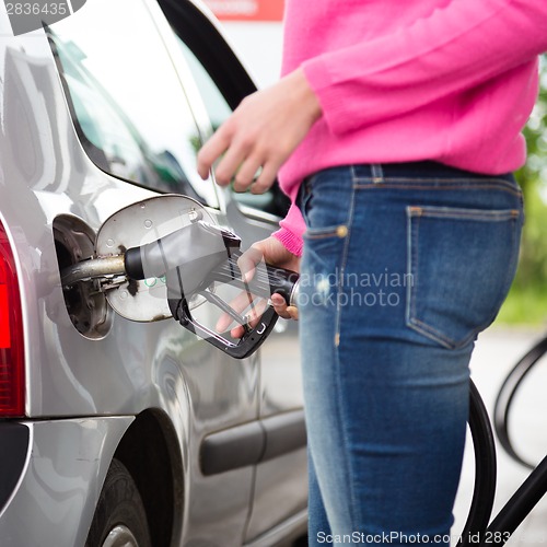 Image of Lady pumping gasoline fuel in car at gas station.