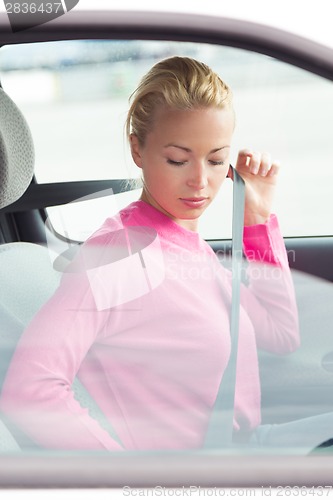 Image of Beautiful woman fastening seat belt.