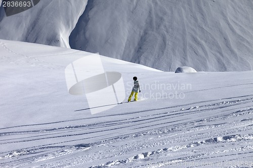 Image of Snowboarder downhill on off piste slope with newly-fallen snow