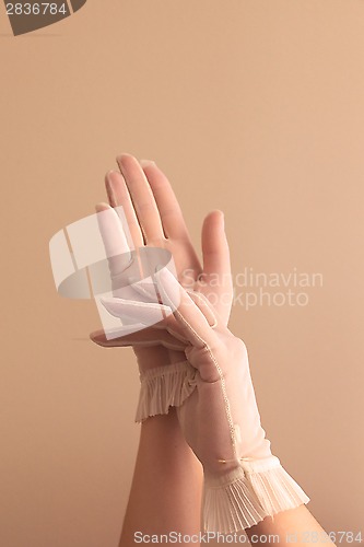 Image of female hands adjusting vintage sheer gloves