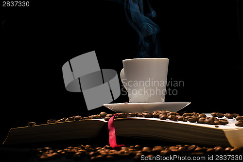 Image of Coffee cup with coffee beans with old book