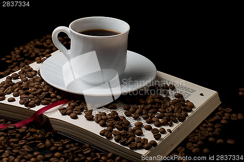 Image of Coffee cup with coffee beans with old book