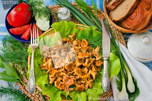 Image of Fried mushrooms of chanterelle on a dish together with lettuce l