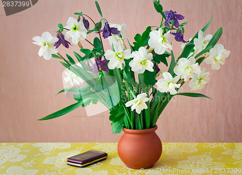 Image of Blossoming narcissuses in a vase on a table.