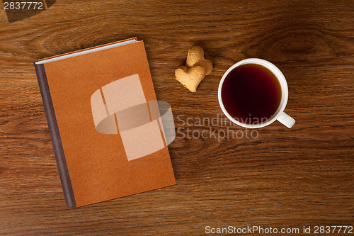 Image of woman with cup of tea, cookies and book on wood