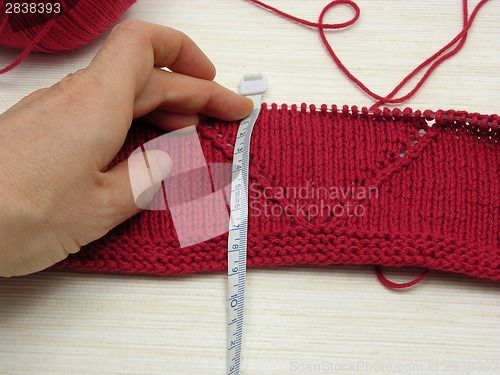 Image of Red knitting with whole pattern and measuring tape