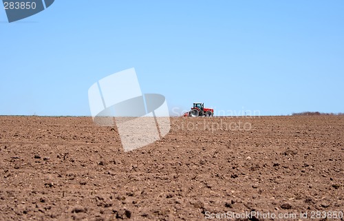 Image of Tractor in a spring field plowing land