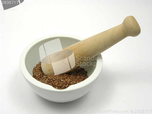 Image of Pestling brown flaxseed in a bowl of chinaware