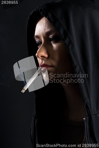 Image of Young woman on a black background smoking a cigarette