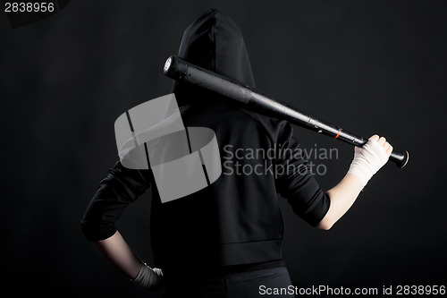 Image of Young woman with a baseball bat. View from the back. hoodlum