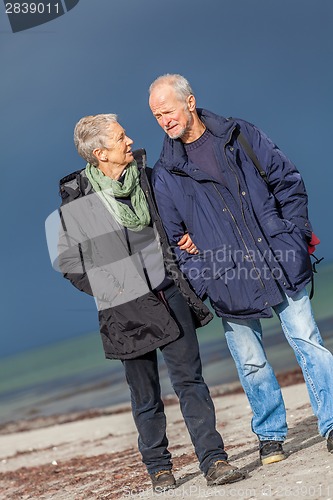 Image of happy elderly senior couple walking on beach