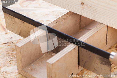 Image of Hand saw cutting through a beam of wood