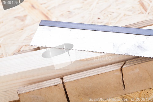 Image of Hand saw cutting through a beam of wood