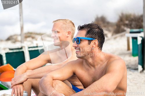 Image of Two handsome young men chatting on a beach