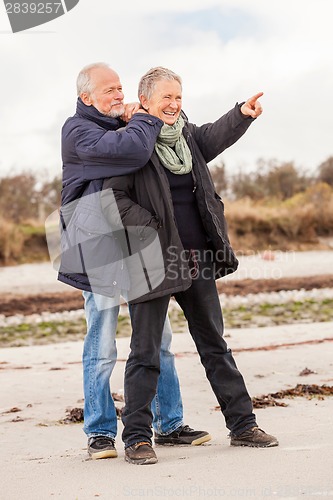 Image of happy elderly senior couple walking on beach