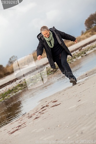 Image of Happy senior woman frolicking on the beach