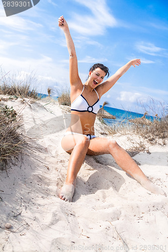 Image of Beautiful woman sitting on golden beach sand