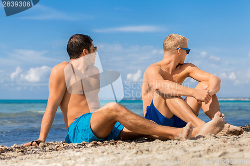 Image of Two handsome young men chatting on a beach