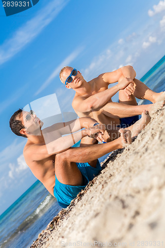 Image of Two handsome young men chatting on a beach