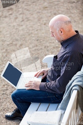 Image of Man sitting on a bench using a laptop